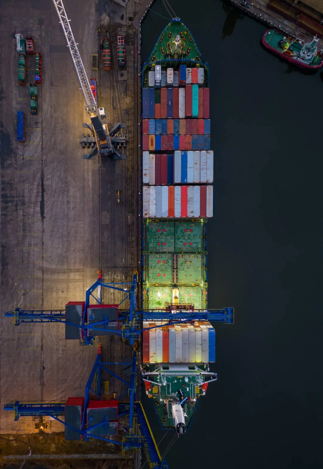 A container ship being loaded alongside a quay, seen from above at dusk