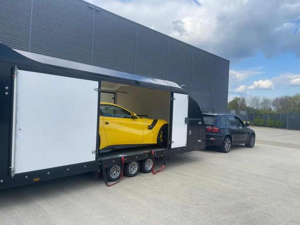 A yellow Ferrari loaded in an enclosed car trailer