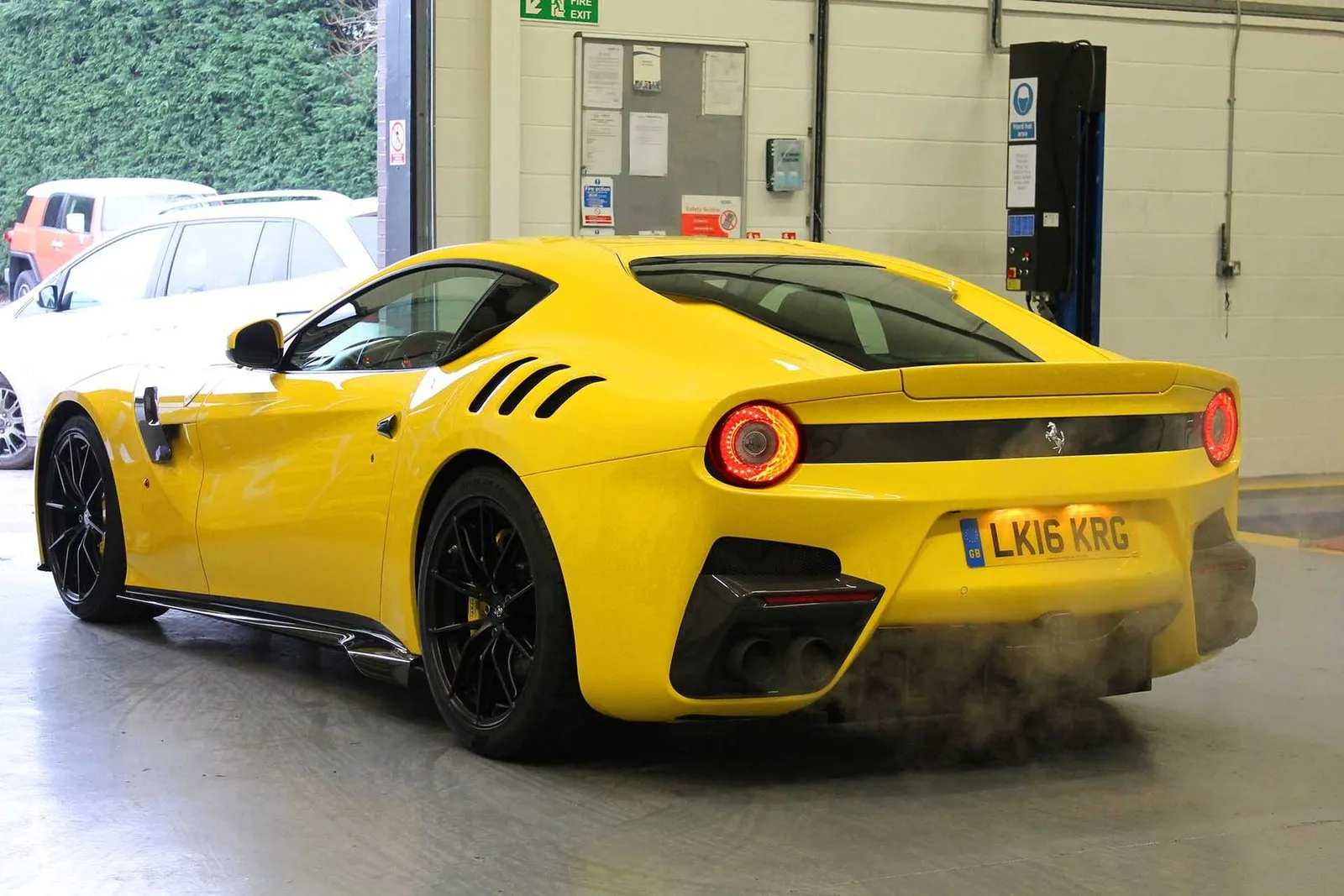 A yellow Ferrari on UK plates in a workshop, one of the supercars My Car Import has imported